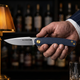 Musketeer folding knife held in hand at a whiskey bar